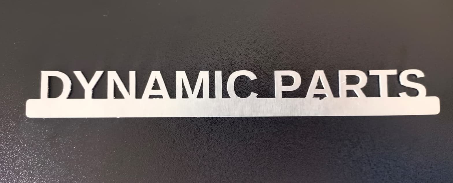 Schriftzug „DYNAMIC PARTS“ aus Metall, lasergeschnitten, auf einer Leiste