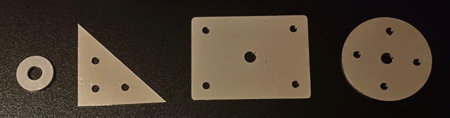 Lasergeschnittene Teile nebeneinander: Unterlegscheibe, Knotenblech, Platte mit Bohrungen und Kreisscheibe
